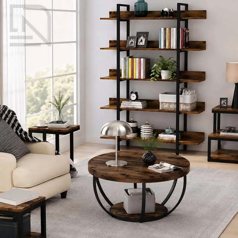 A round coffee table with a dark wood top and black metal circular base is shown in a styled living room next to a cream sofa and a tall black metal bookshelf.