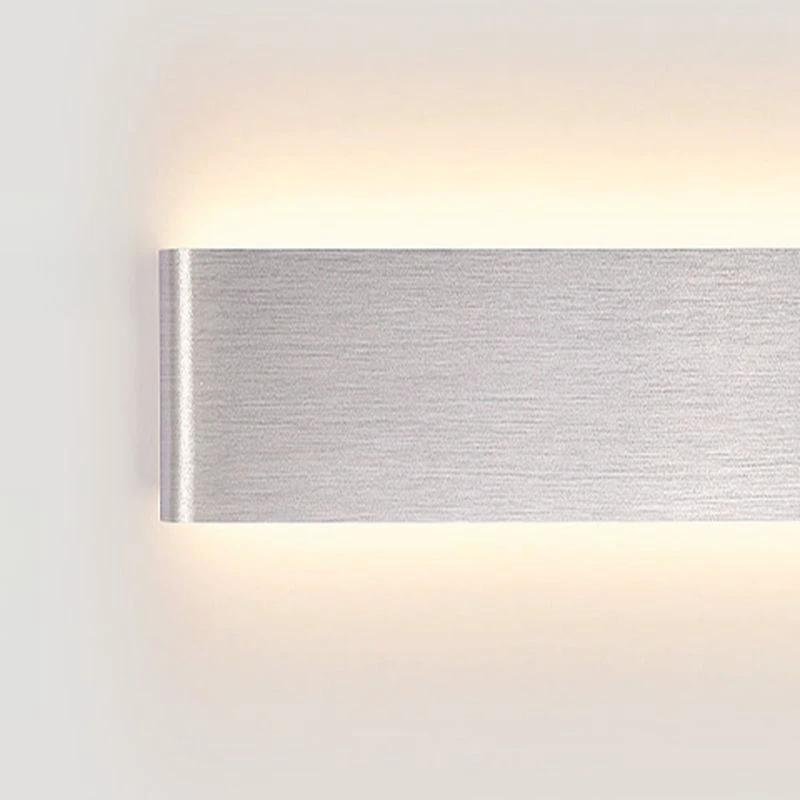 Wall light in brushed aluminium, wall-mounted with up and down LED glow on a white wall.