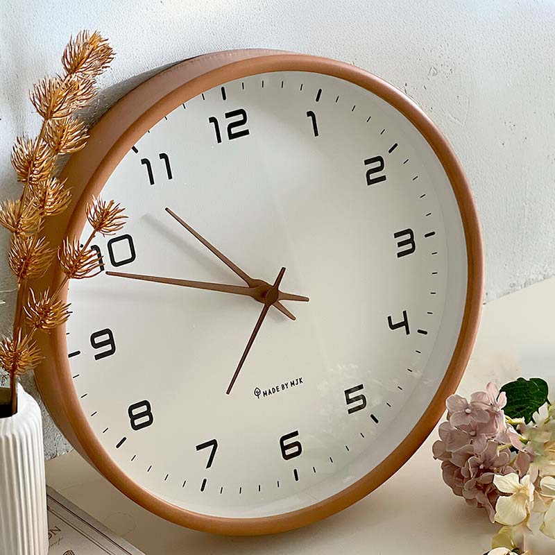Nordic Wooden Wall Clock on a table; white dial, black numerals, brown hands, wooden frame beside dried plants.