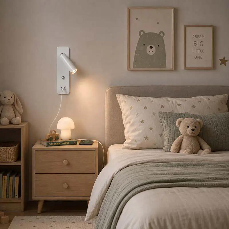 A styled children's bedroom featuring a white adjustable wall-mounted reading light on a beige wall, next to a wooden nightstand with a mushroom lamp, books, and a plush bunny. The foreground shows a bed with star-patterned pillows and a teddy bear.